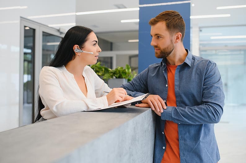 Nice friendly woman talking to the client while standing at the reception.